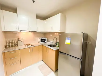 a kitchen with white cabinets and a stainless steel refrigerator at Luxury BGC Condo Across Mitsukoshi #upt112b in Manila