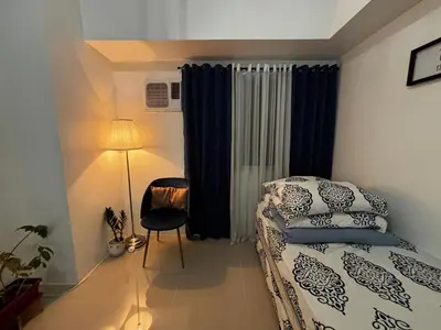 a small bedroom with a bed and a lamp at Calicon Suites in Manila
