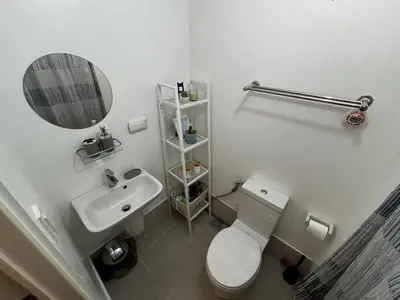 a bathroom with a toilet and a sink and a mirror at Calicon Suites in Manila