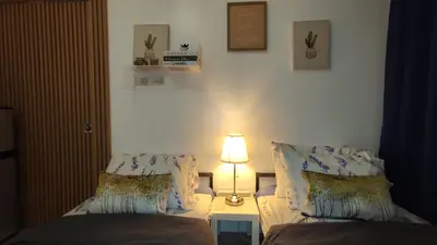 a bedroom with two beds and a lamp on a table at Calicon Suites in Manila
