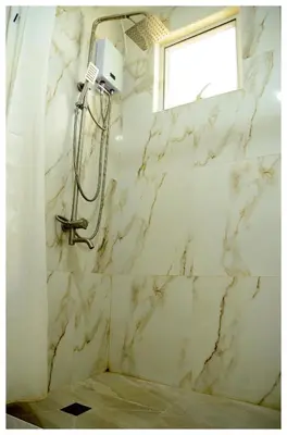 a shower in a bathroom with white marble walls at Brianna's haven property rental in Manila