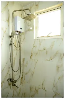 a shower in a bathroom with a white marble wall at Brianna's haven property rental in Manila
