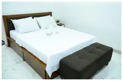 a bedroom with a white bed with a brown ottoman at Brianna's haven property rental in Manila