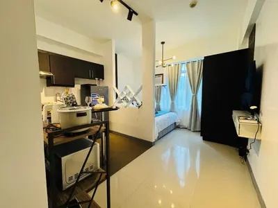 a kitchen with a counter and a room with a bed at Your perfect retreat in Stamford! Enjoy our stylish, fully furnished studio just steps away from the vibrant Venice Mall in Manila