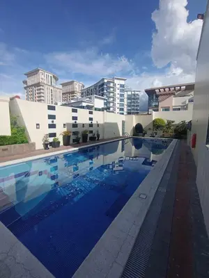 a large swimming pool with buildings in the background at Your perfect retreat in Stamford! Enjoy our stylish, fully furnished studio just steps away from the vibrant Venice Mall in Manila