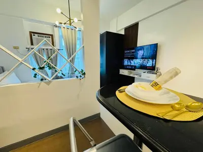 a room with a table with a plate of food on it at Your perfect retreat in Stamford! Enjoy our stylish, fully furnished studio just steps away from the vibrant Venice Mall in Manila