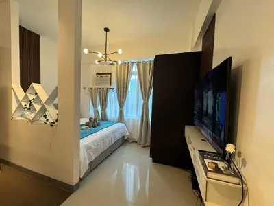 a bedroom with a bed and a flat screen tv at Your perfect retreat in Stamford! Enjoy our stylish, fully furnished studio just steps away from the vibrant Venice Mall in Manila