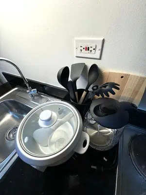 a kitchen counter with a sink and a pot with utensils at Santa Place Shore Residences Tower A in Manila