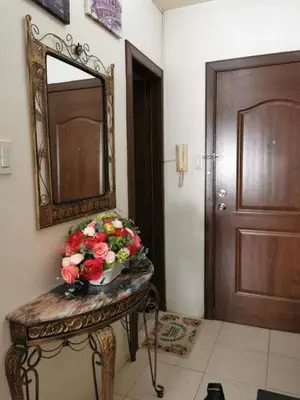 a vase of flowers on a table in front of a mirror at Sweetheart Casa Vacanza in Manila