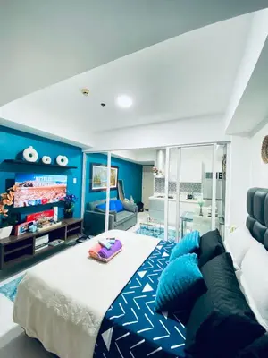 a bedroom with blue walls and a bed and a couch at Cozy Inn Azure in Manila