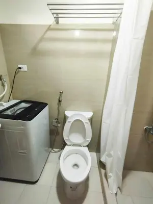 a bathroom with a toilet with a shower curtain at Shore 2 Residences by Casa Stellar in Manila