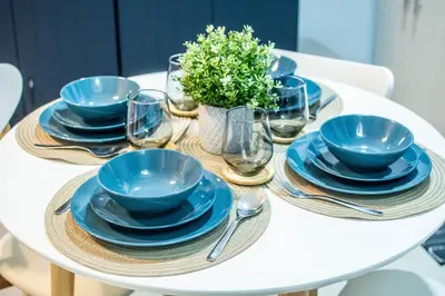 a white table with blue plates and glasses and a plant at Elivion Staycations at McKinley Hill, near Venice, BGC, with Pool & Wifi in Manila