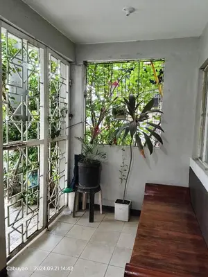 a room with windows with a chair and a plant at Family Airconditioned Room with Balcony & Parking in Cabuyao 2-storey house in Cabuyao