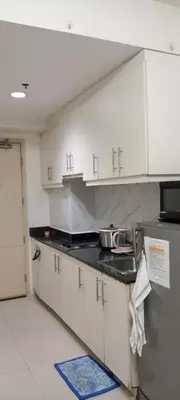 a kitchen with white cabinets and a black counter top at Sea Residences MOA by -MJ in Manila