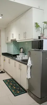 a kitchen with white cabinets and a stainless steel refrigerator at Sea Residences MOA by -MJ in Manila