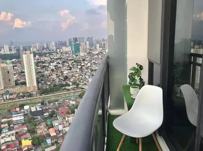 a balcony with two chairs and a view of a city at Amazing 1 bedroom with pool, gym and stunning view at heart of Makati in Manila