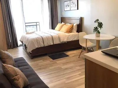 a bedroom with a bed and a table with a couch at Amazing 1 bedroom with pool, gym and stunning view at heart of Makati in Manila