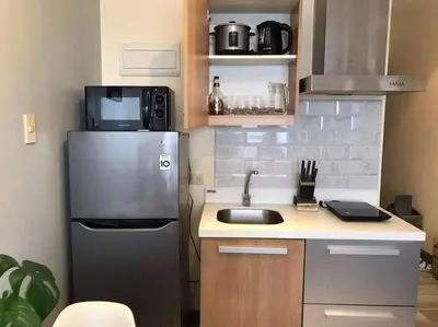 a small kitchen with a sink and a refrigerator at Amazing 1 bedroom with pool, gym and stunning view at heart of Makati in Manila