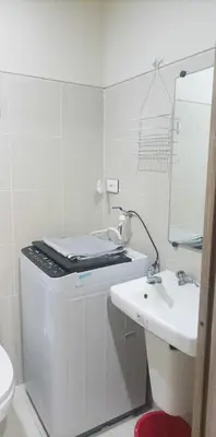 a white bathroom with a sink and a mirror at Natalie's Place in Mall of Asia Complex in Manila