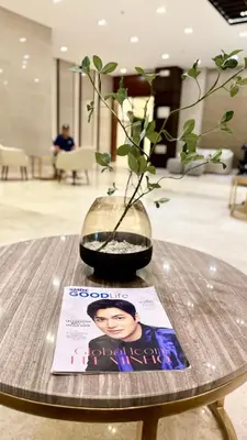 a vase with a plant on a table with a magazine at Home of the GoodVibes Red Residences Makati in Manila