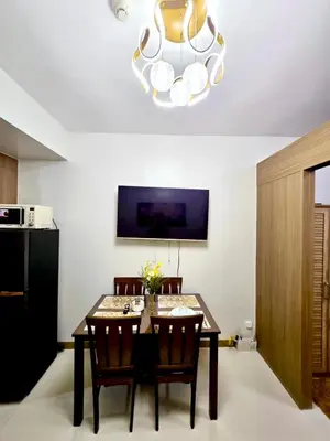 a dining room with a table and a chandelier at Home of the GoodVibes Red Residences Makati in Manila