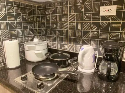 a kitchen counter with a stove with pots and pans at 1BR CONDO Fame Residences Mandaluyong- Be My Guest Staycation- Near SM Megamall, Greenfield District, & Ortigas in Manila