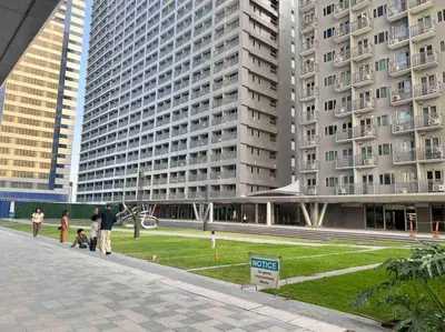 a group of people standing in front of a large building at 1BR CONDO Fame Residences Mandaluyong- Be My Guest Staycation- Near SM Megamall, Greenfield District, & Ortigas in Manila