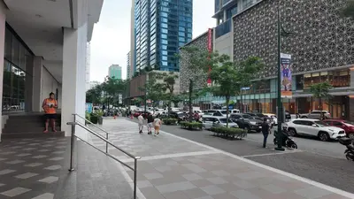 people walking down a sidewalk in a city with cars at Cozy 1 bedroom condo in Uptown BGC in Manila