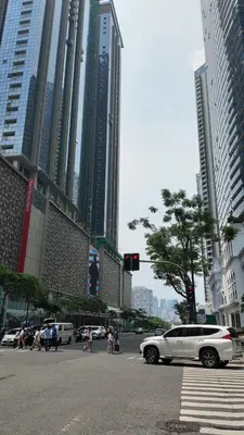 a white car driving down a city street with tall buildings at Cozy 1 bedroom condo in Uptown BGC in Manila