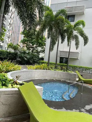 a small pool with a green chair and palm trees at The Viceroy Tower1 condominium in Manila