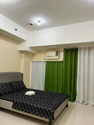 a bedroom with a bed and a green curtain at The Viceroy Tower1 condominium in Manila