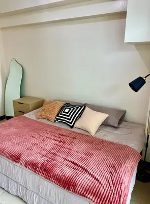 a bed with pillows on it in a bedroom at Luxury Bauhaus inspired apartment near Makati in Manila