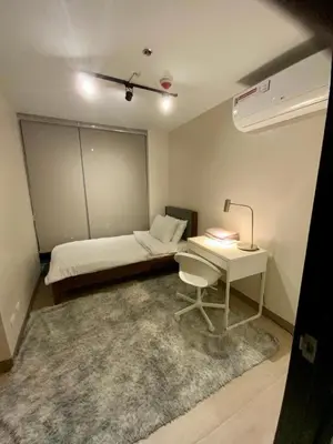 a small room with a bed and a desk with a lamp at Luxurious 2 BR at Eastwood City in Manila