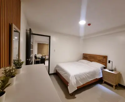 a white bedroom with a bed and a mirror at Flat 35, Unit 2A in Manila