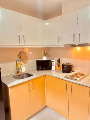 a kitchen with white cabinets and a sink and a microwave at 1BR Luxury unit in Uptown Parksuites -Walking distance to Malls in Manila