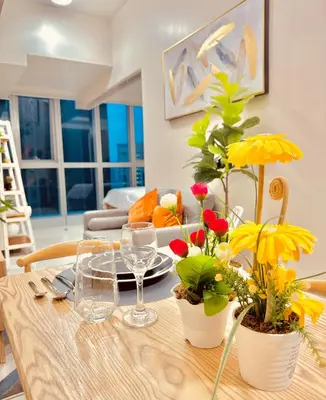 a dining room table with flowers and glasses on it at 1BR Luxury unit in Uptown Parksuites -Walking distance to Malls in Manila