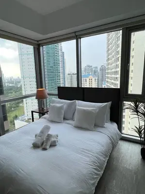 a large white bed in a room with large windows at Stylish 1BR At Avant BGC in Manila