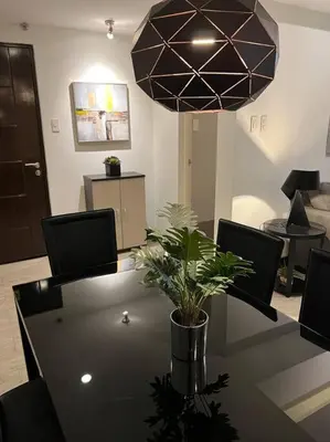 a room with a table with chairs and a pendant light at Stylish 1BR At Avant BGC in Manila