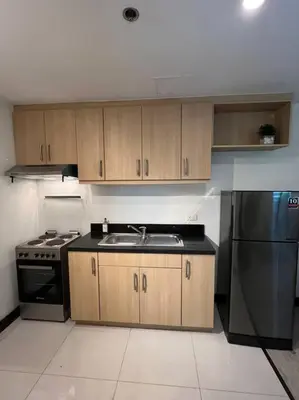 a kitchen with a sink and a stainless steel refrigerator at Stylish 1BR At Avant BGC in Manila