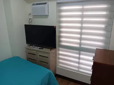 a bedroom with a television and a window with blinds at Smith's Place in Manila