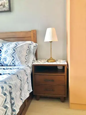 a bed with a night stand with a lamp on it at Cosy 1BR Uptown BGC with Balcony and Swimming Pool in Manila