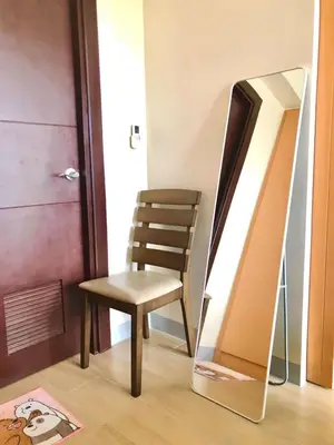 a chair and a mirror next to a door at Cosy 1BR Uptown BGC with Balcony and Swimming Pool in Manila