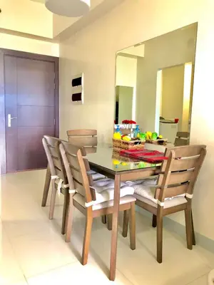 a dining room with a table with chairs and a mirror at Cosy 1BR Uptown BGC with Balcony and Swimming Pool in Manila