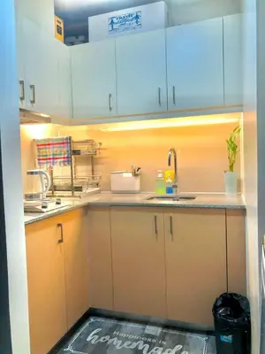 a kitchen with white cabinets and a sink at Cosy 1BR Uptown BGC with Balcony and Swimming Pool in Manila