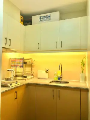a kitchen with white cabinets and a sink at Cosy 1BR Uptown BGC with Balcony and Swimming Pool in Manila