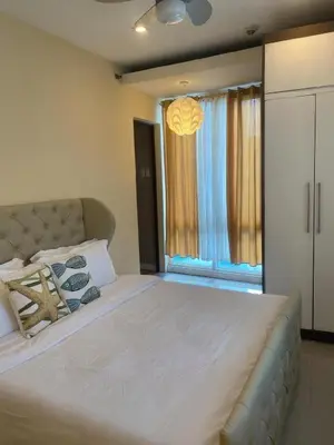 a bedroom with a large bed and a window at Elegant 2BR, 2 BA Suite Beside Eastwood Mall in Manila