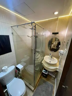 a bathroom with a shower and a toilet and a sink at Elegant 2BR, 2 BA Suite Beside Eastwood Mall in Manila