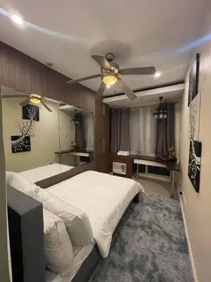 a bedroom with a bed and a ceiling fan at Elegant 2BR, 2 BA Suite Beside Eastwood Mall in Manila