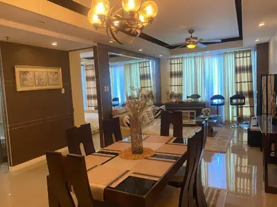 a dining room with a table and a living room at Elegant 2BR, 2 BA Suite Beside Eastwood Mall in Manila