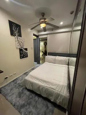 a bedroom with a bed and a ceiling fan at Elegant 2BR, 2 BA Suite Beside Eastwood Mall in Manila